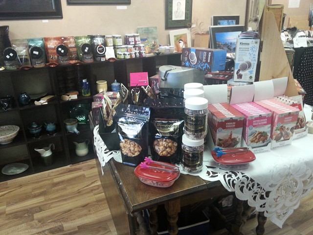 Table display of packaged snacks and jars beside shelves of pottery and framed art.