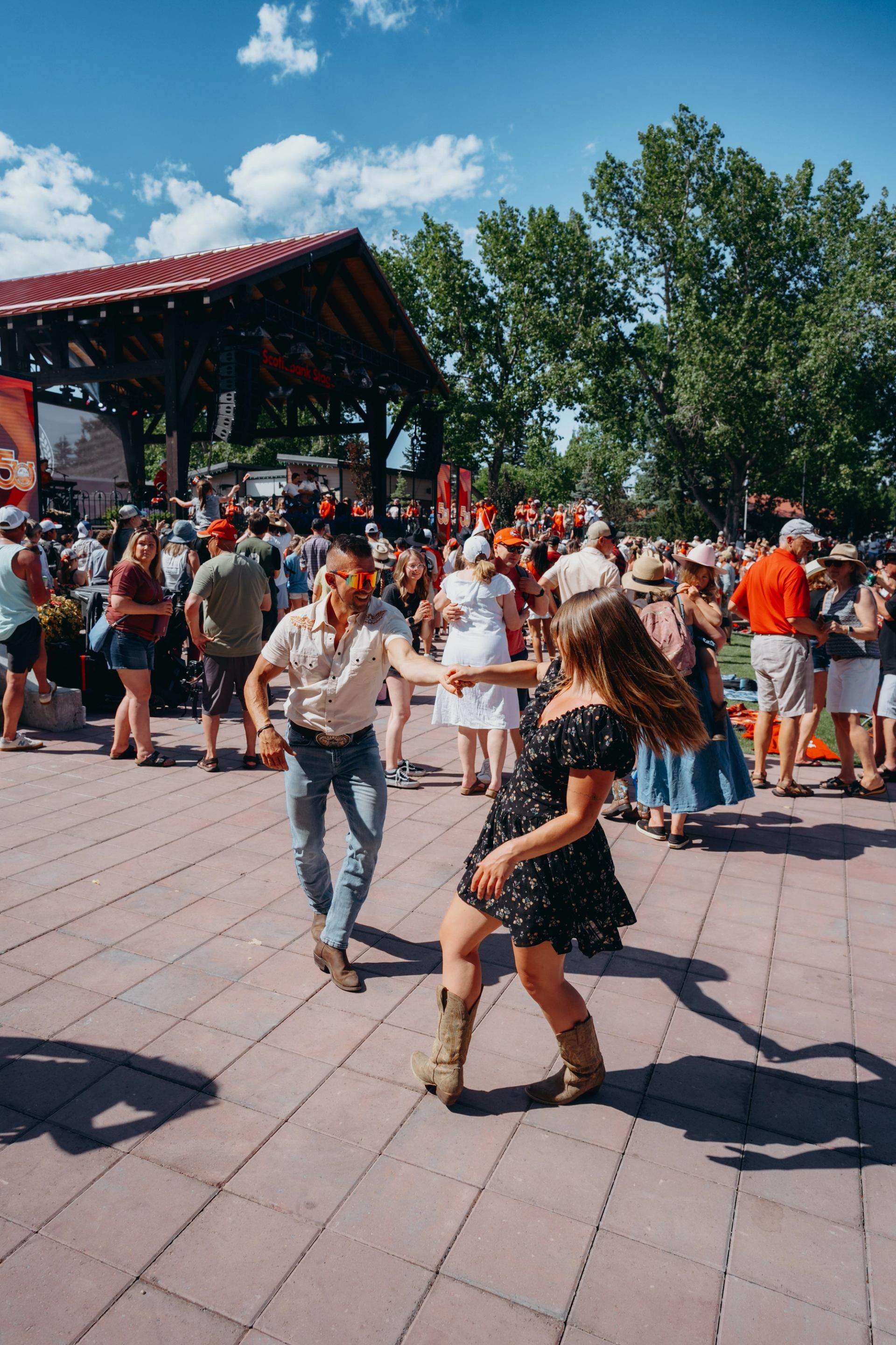 Festivalgoers dancing in a lively outdoor crowd near a stage