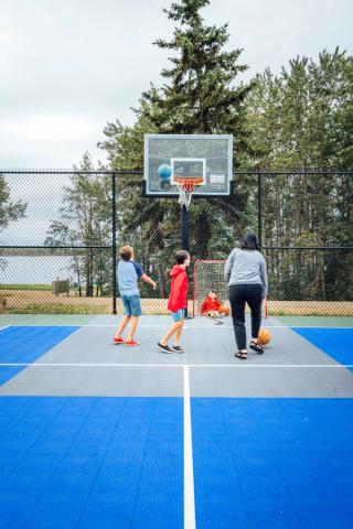 A family playing basketball at a court at Keiver's Lake Campground.