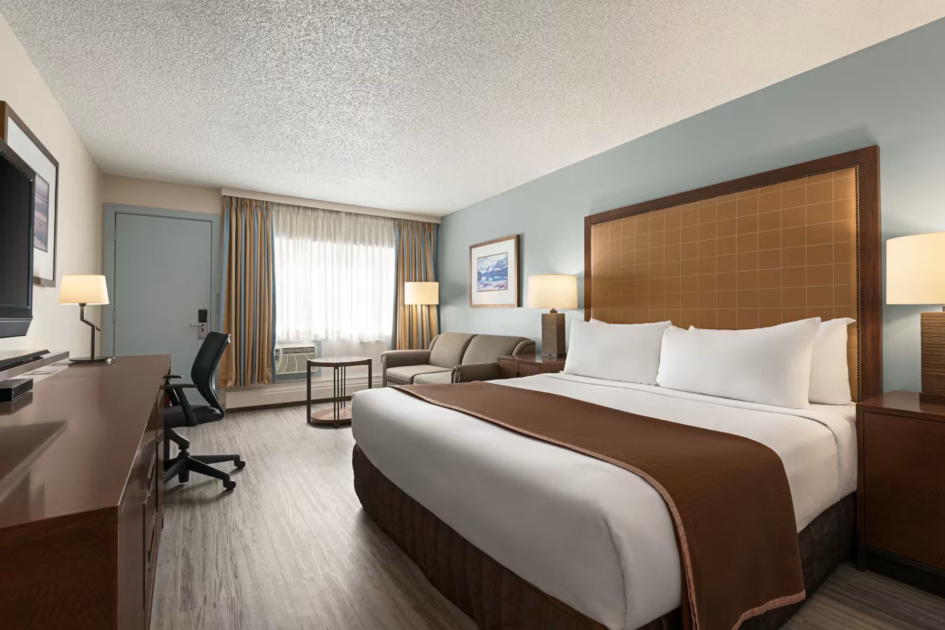 Travelodge Calgary South features a spacious guest room with a king bed, desk, and seating area.