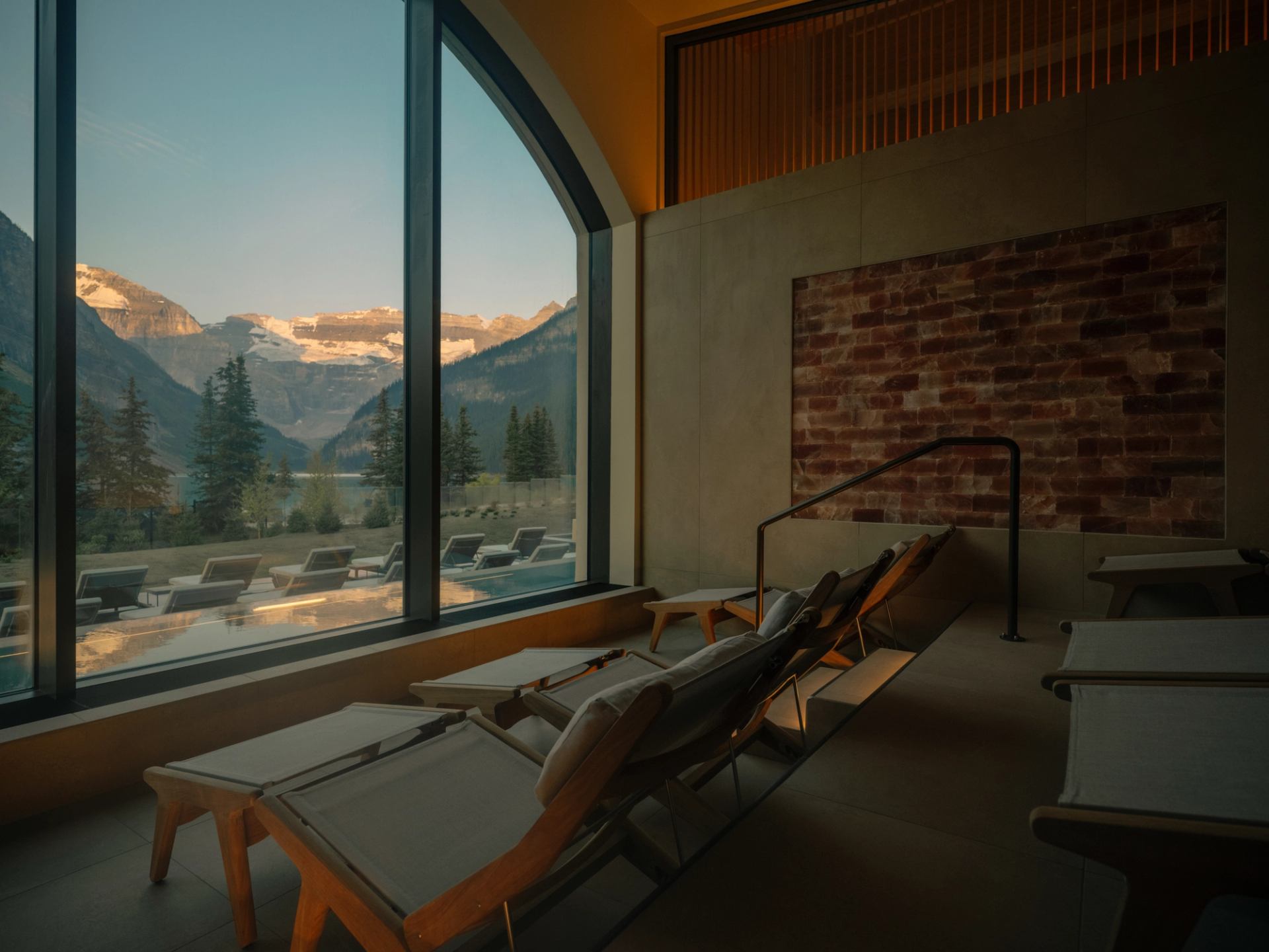 A row of reclined chairs overlooks a spa deck and the Canadian Rockies.