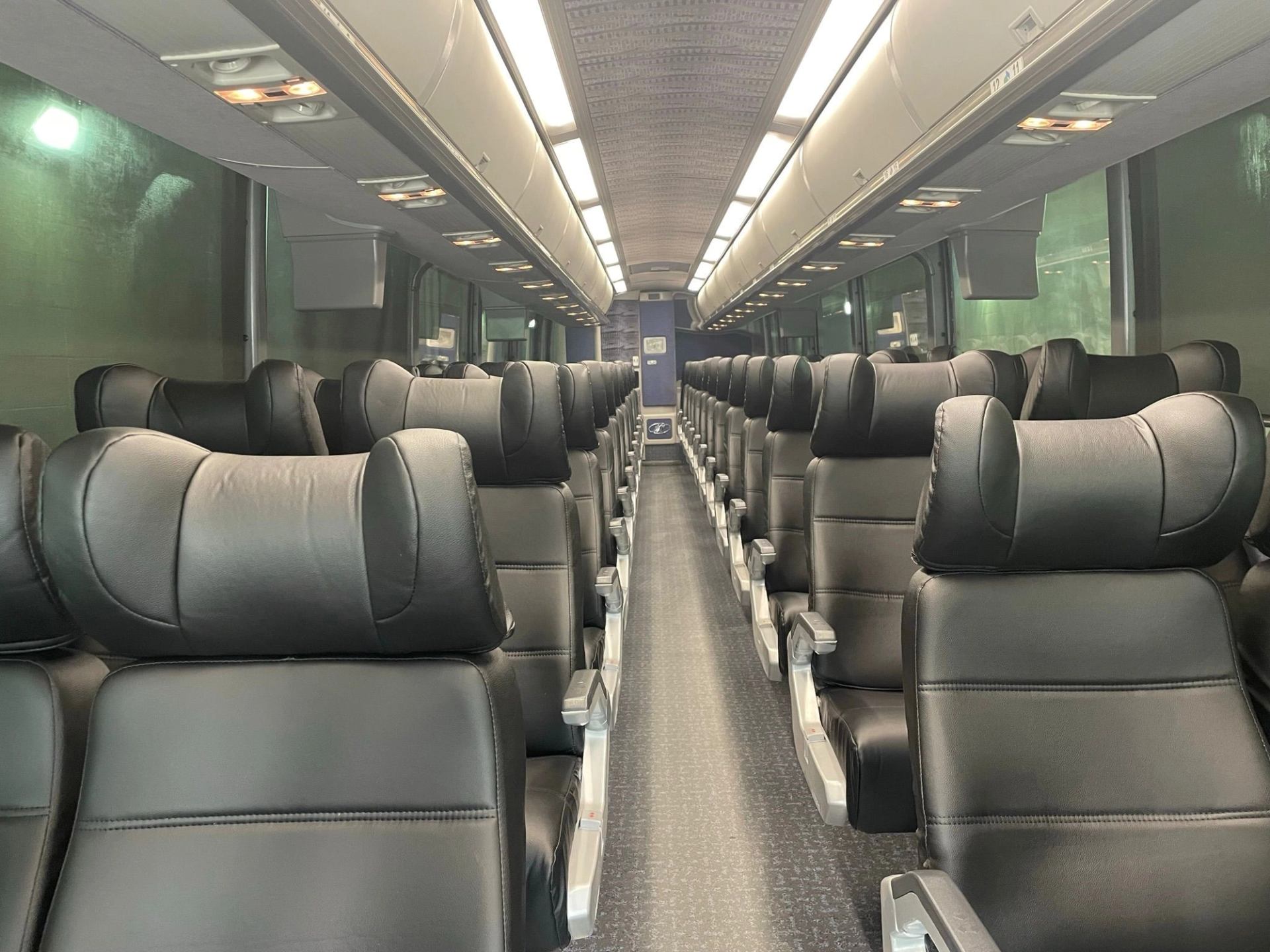 The passenger area of a charter bus with leather seats and neck support.