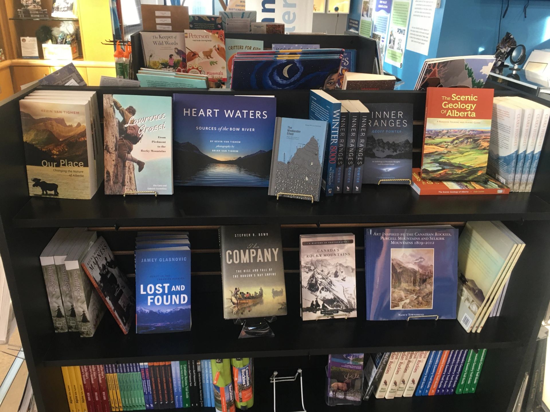 Museum bookstore display with books on Alberta, Rockies, and natural history, neatly arranged on black shelves.