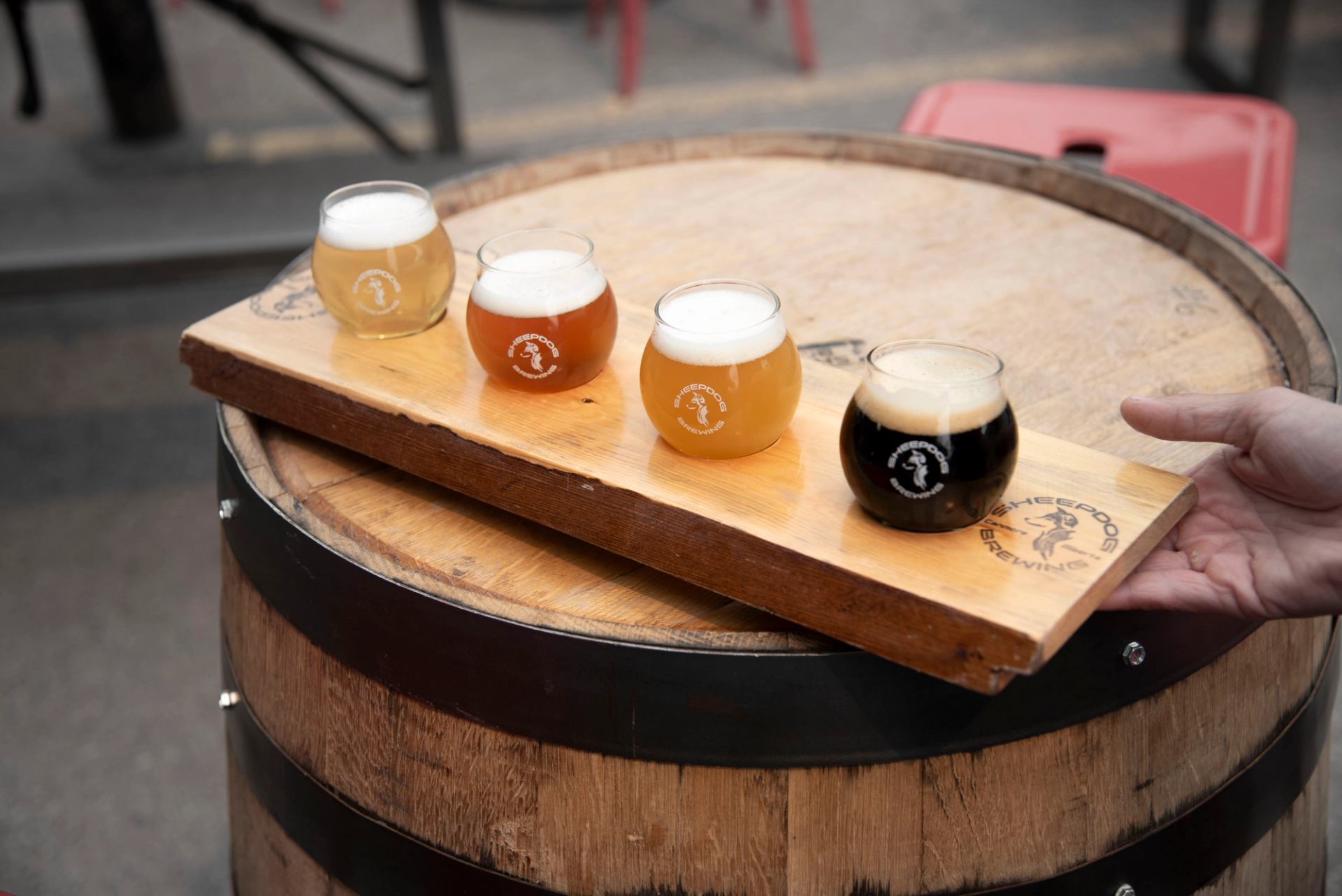 Beer flight with four foamy samples rests on a wooden barrel.