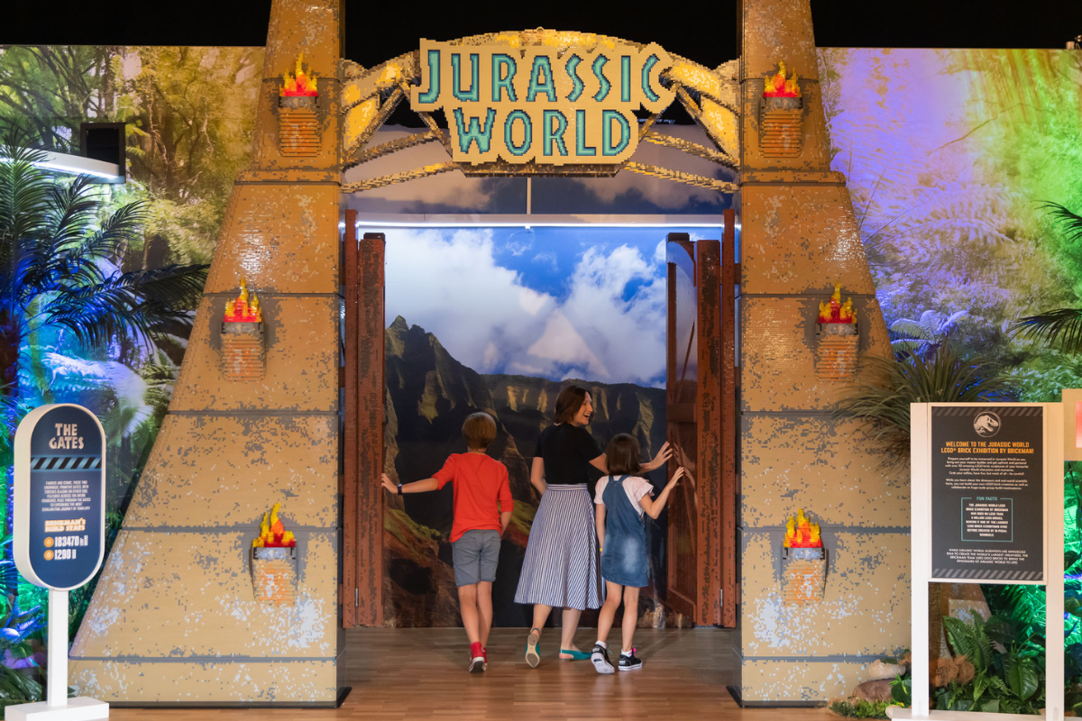 Visitors walk through flaming gates into the LEGO Jurassic World jungle exhibit.