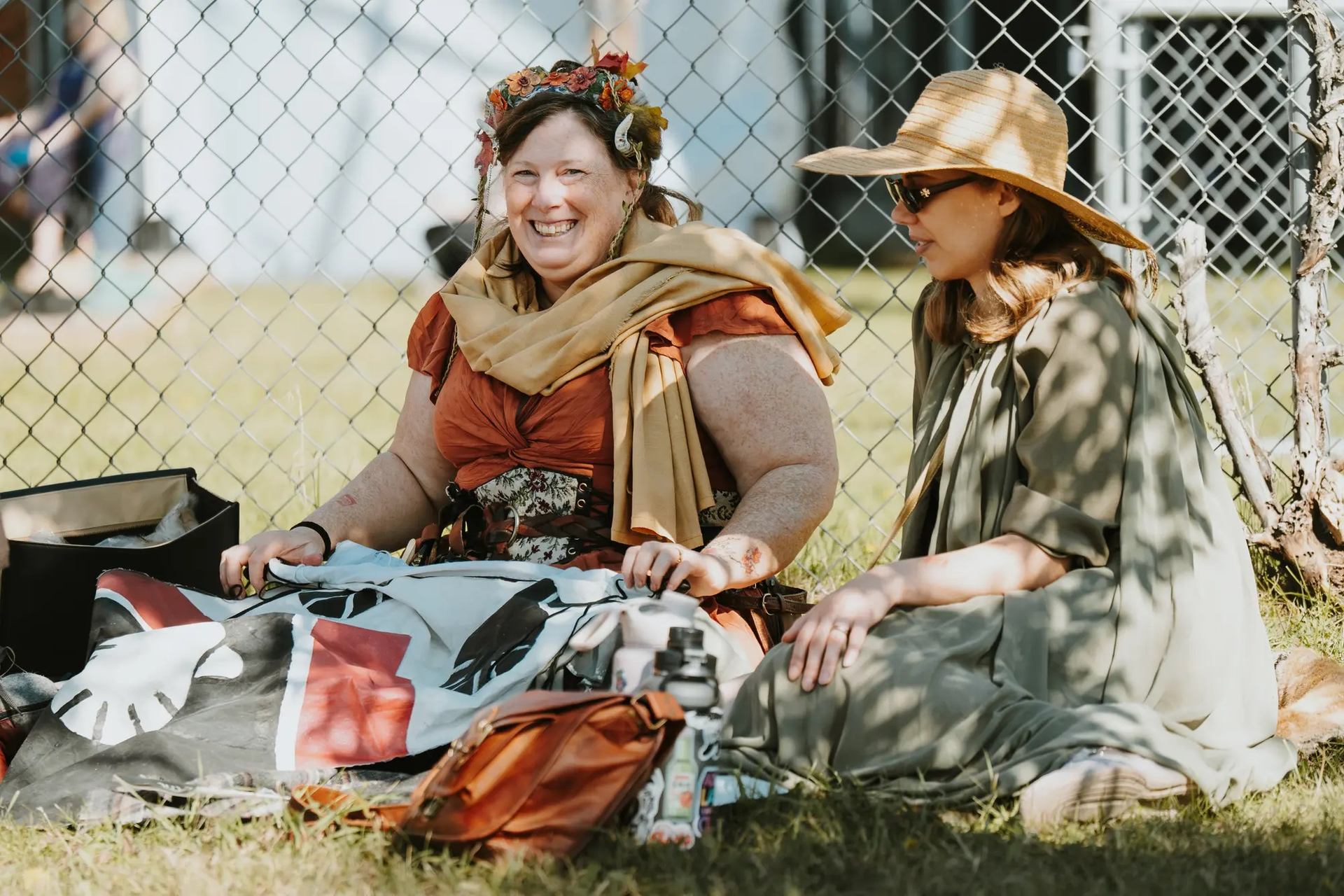 Two people in festive attire sit on grass at Vegreville Medieval Faire.
