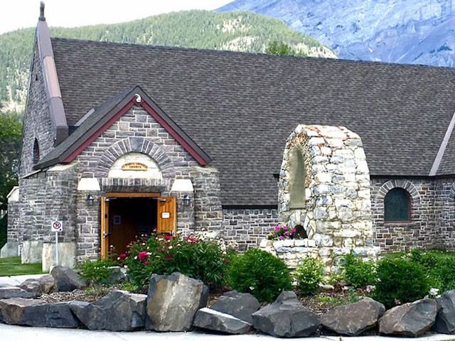Stone exterior of St. Mary’s Parish with archway and mountain backdrop.