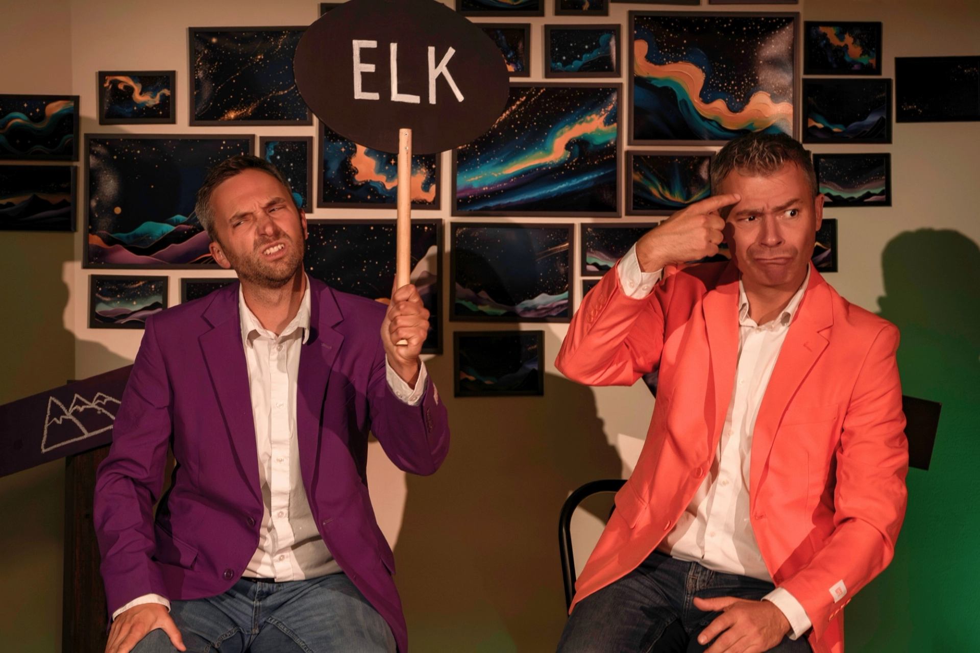 Two performers holding a sign that says ELK during a comedic scene
