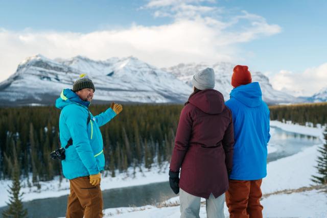 A guide explains the local area while snowshoeing with a couple