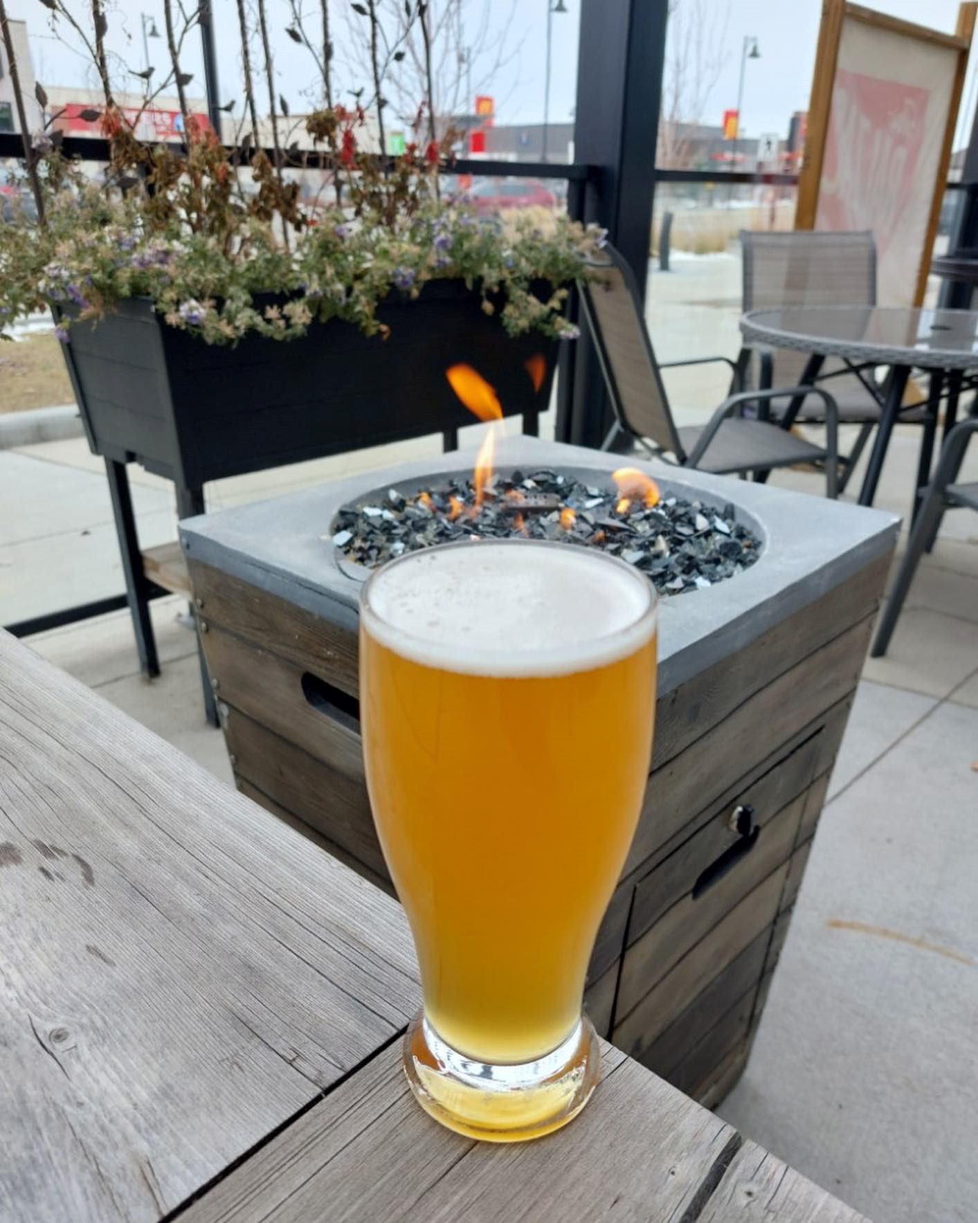 A brew on a patio table outside by a firepit.