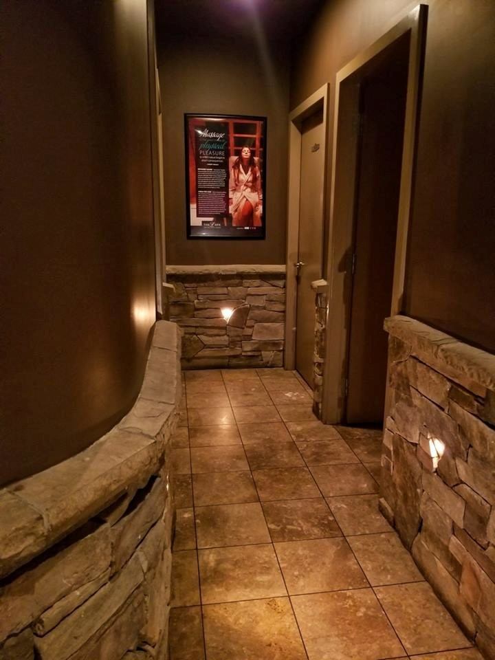 Hallway with stone walls, tiled floor, and framed spa poster at The L Spa & Wellness Centre.