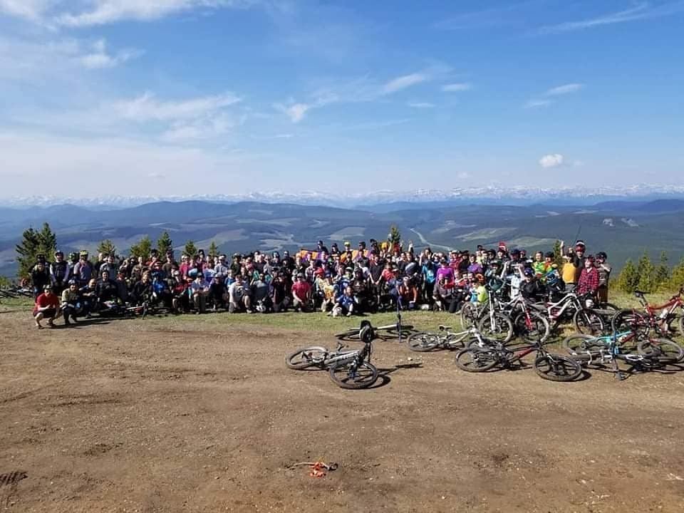 Cyclists gathered on a mountain clearing with bikes and panoramic views.