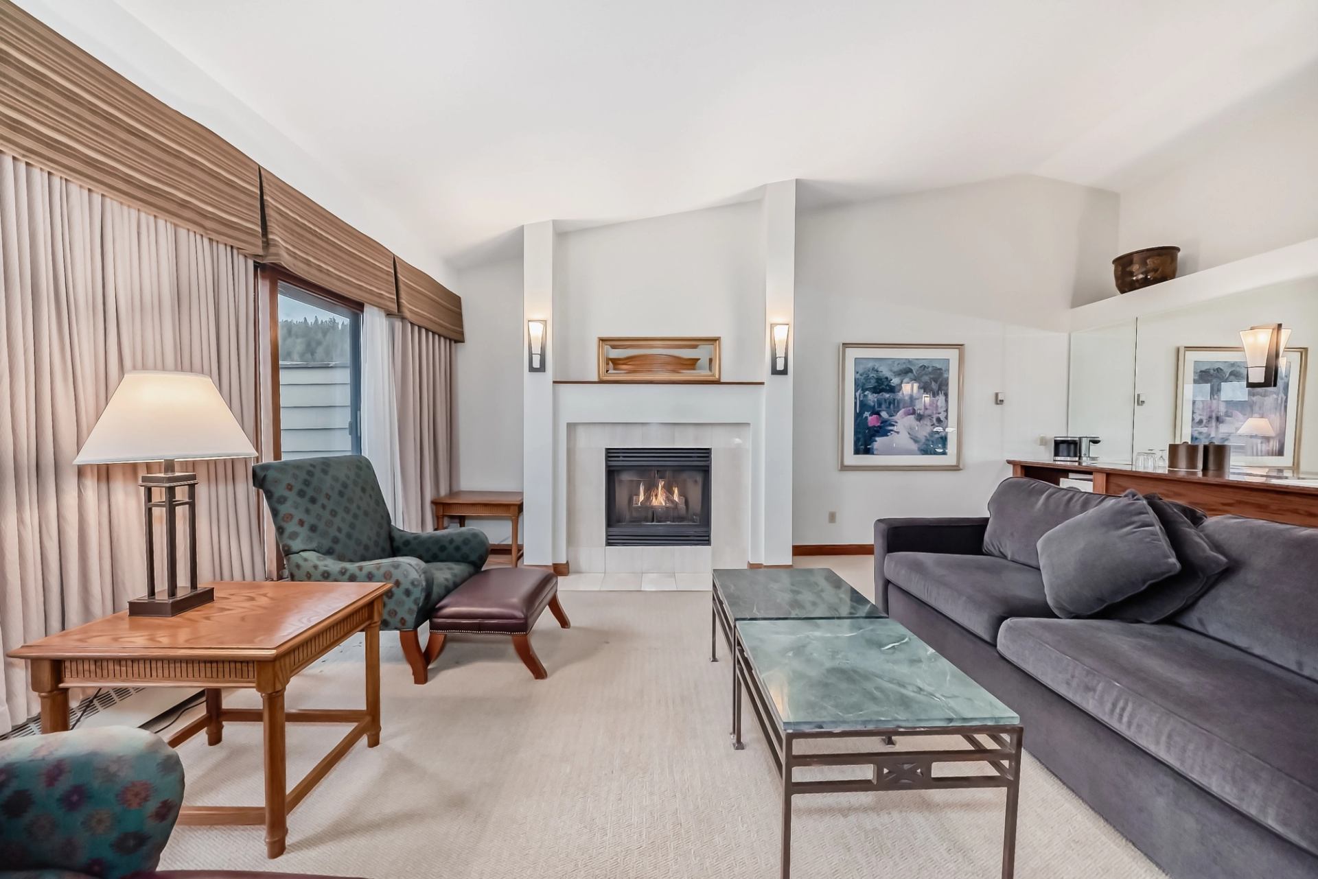 Cozy living room featuring a fireplace, sofa, armchair, and coffee tables with lamps