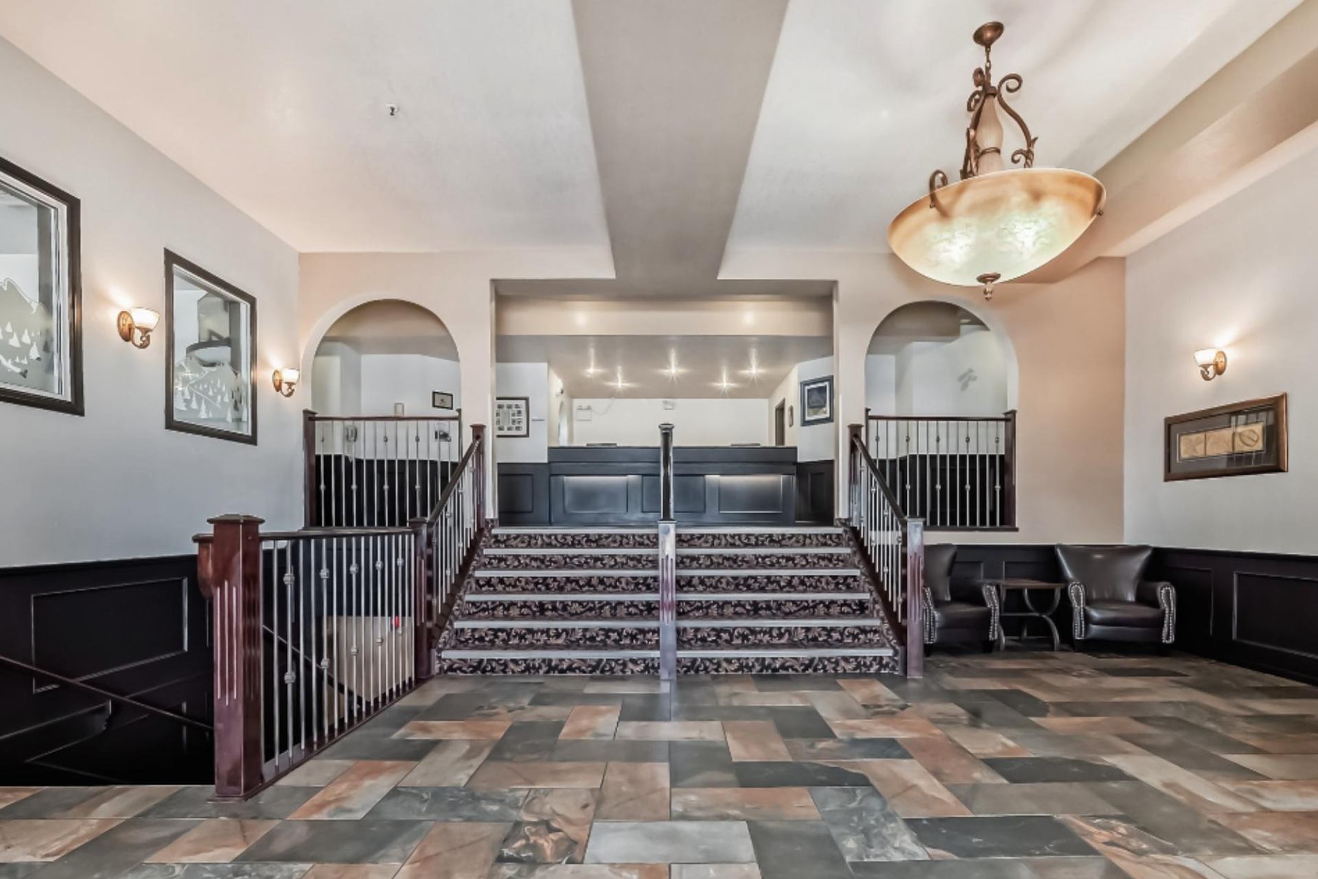 Elegant hotel lobby with tiled floor, staircase, chandelier, and seating area at Grande Cache Inn.