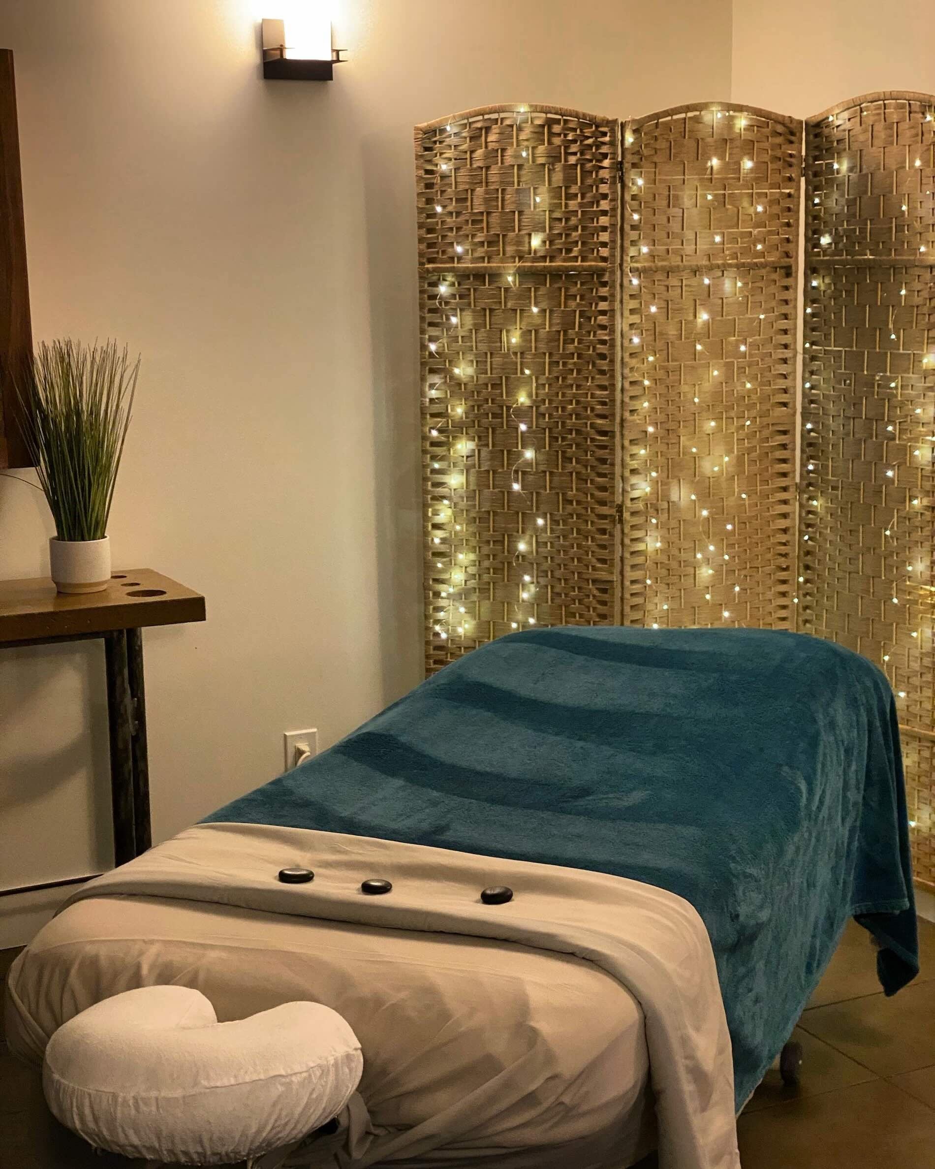 Cozy massage room with soft lighting and stones on the table.