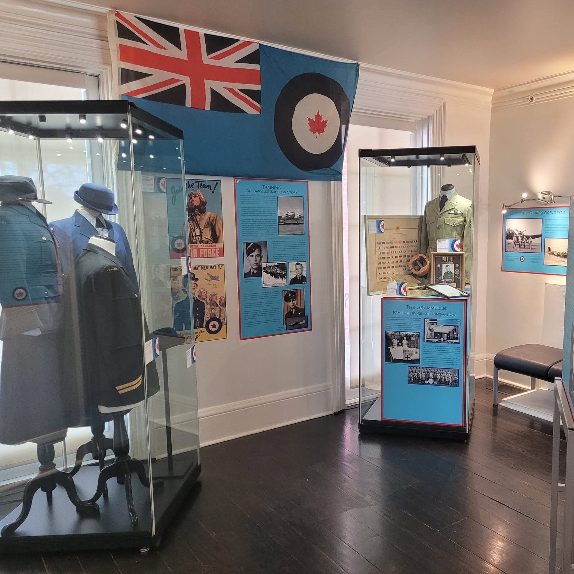 Museum exhibit with military uniforms, Canadian flag, historical photos and informational display panels.