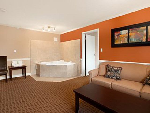 Cozy suite featuring a beige sofa, coffee table, and a large corner bathtub.