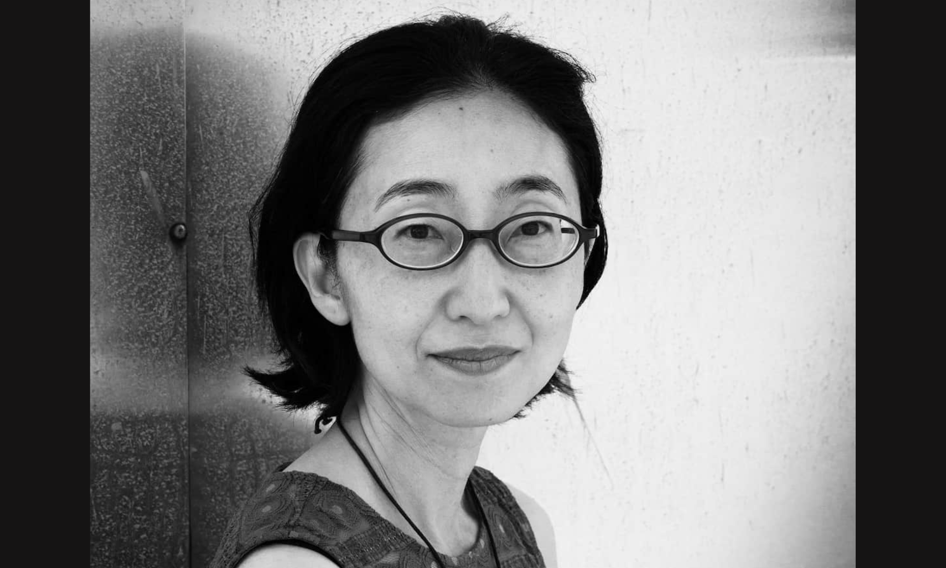 Black and white portrait of a woman with short dark hair and oval glasses looking forward.