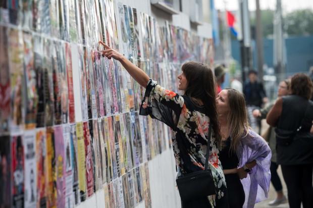 Fringers peruse a wall of posters, trying to choose which of 215 theatre shows they should see at the Edmonton Fringe Festival.