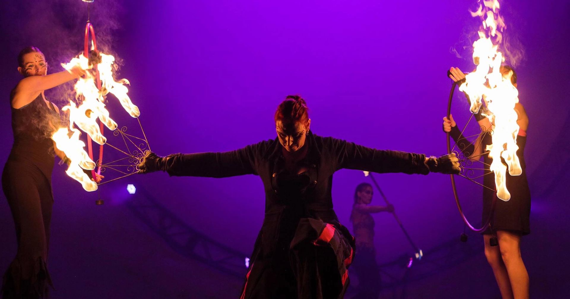 Fire dancers perform with flaming hoops onstage under purple lighting, with ONE logo above.