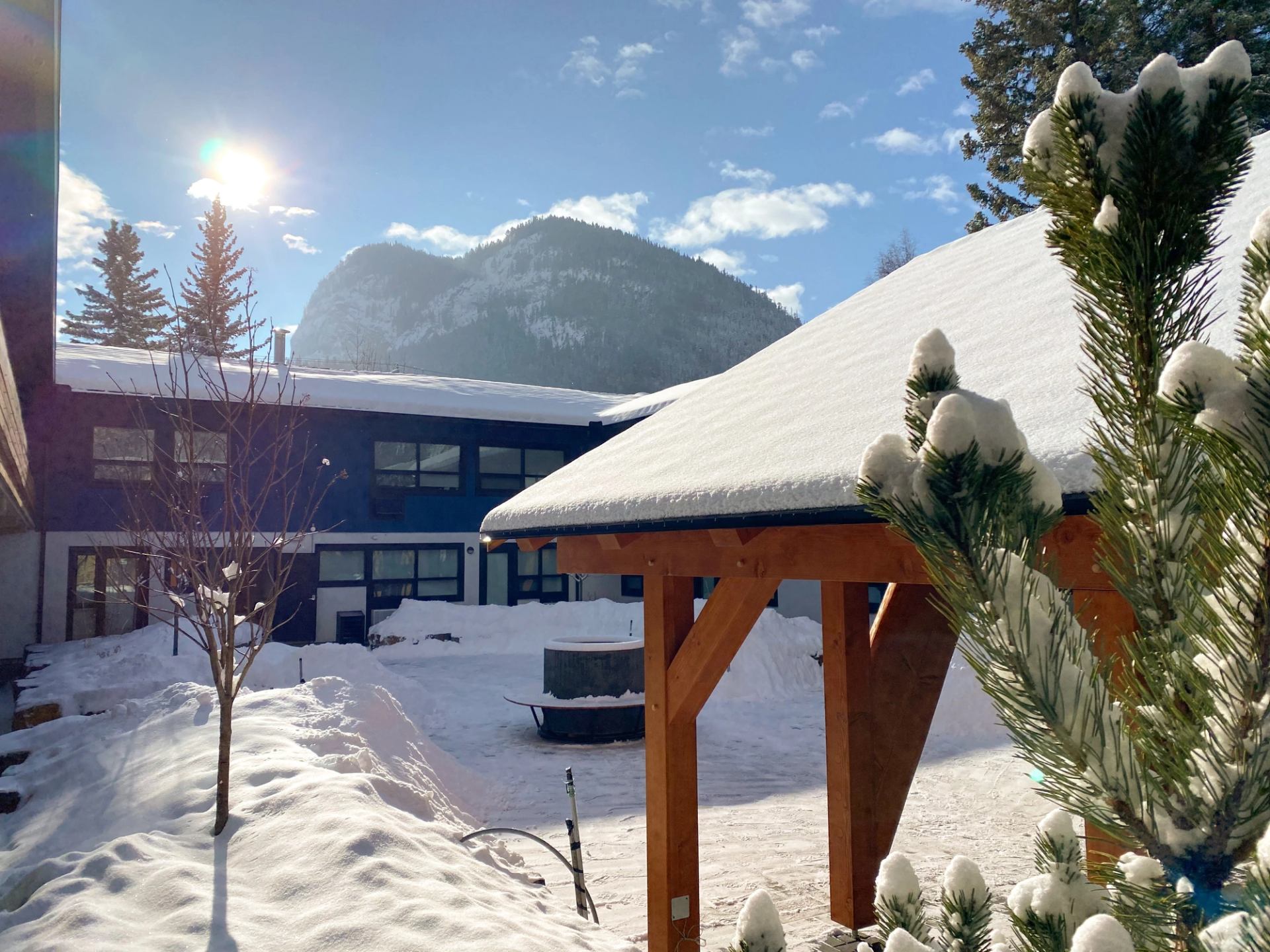 Snowy courtyard at The Dorothy Motel with mountain views and blue skies.
