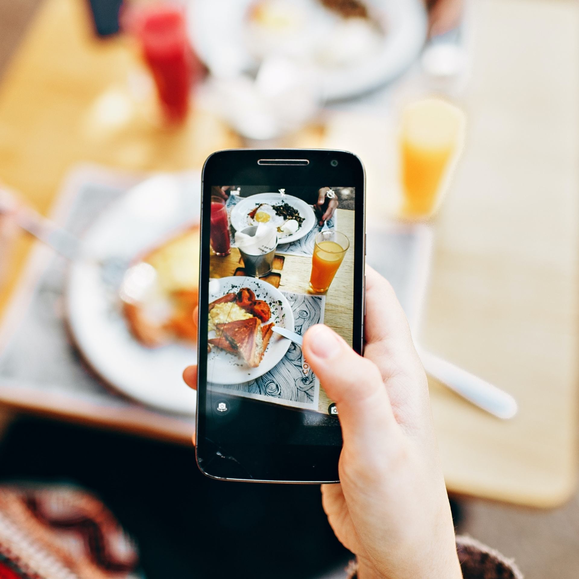 Hand holding phone to snap photo of plated food during 124th Food Walk Tour.