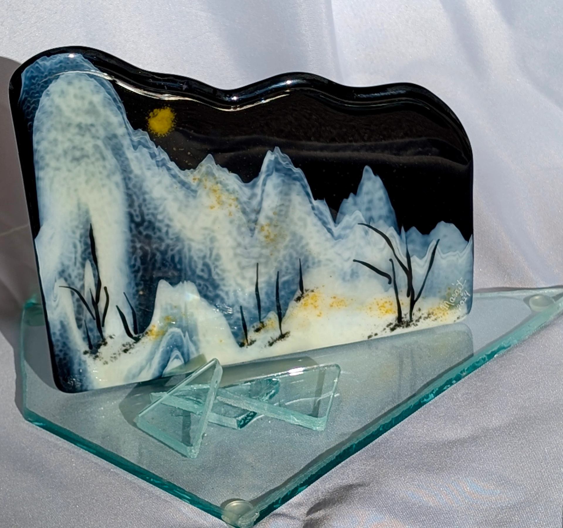 Fused glass with a winter scenery on it.