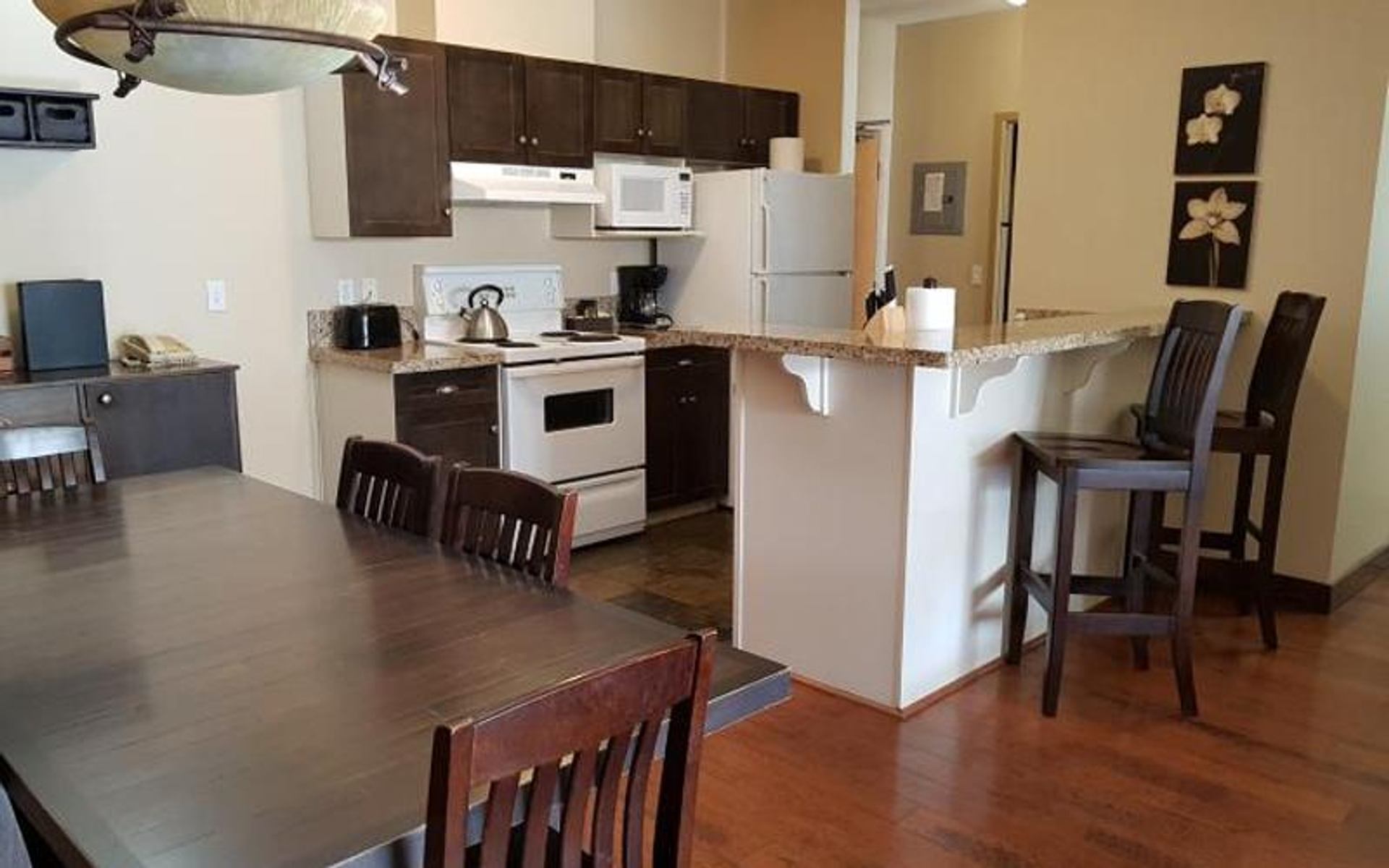 Open kitchen and dining area with dark wood furniture and white appliances.