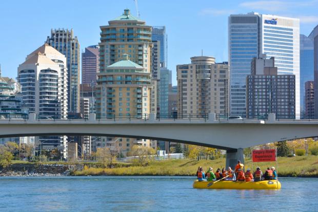 Tour group floating down the Bow River with downtown Calgary in the background.