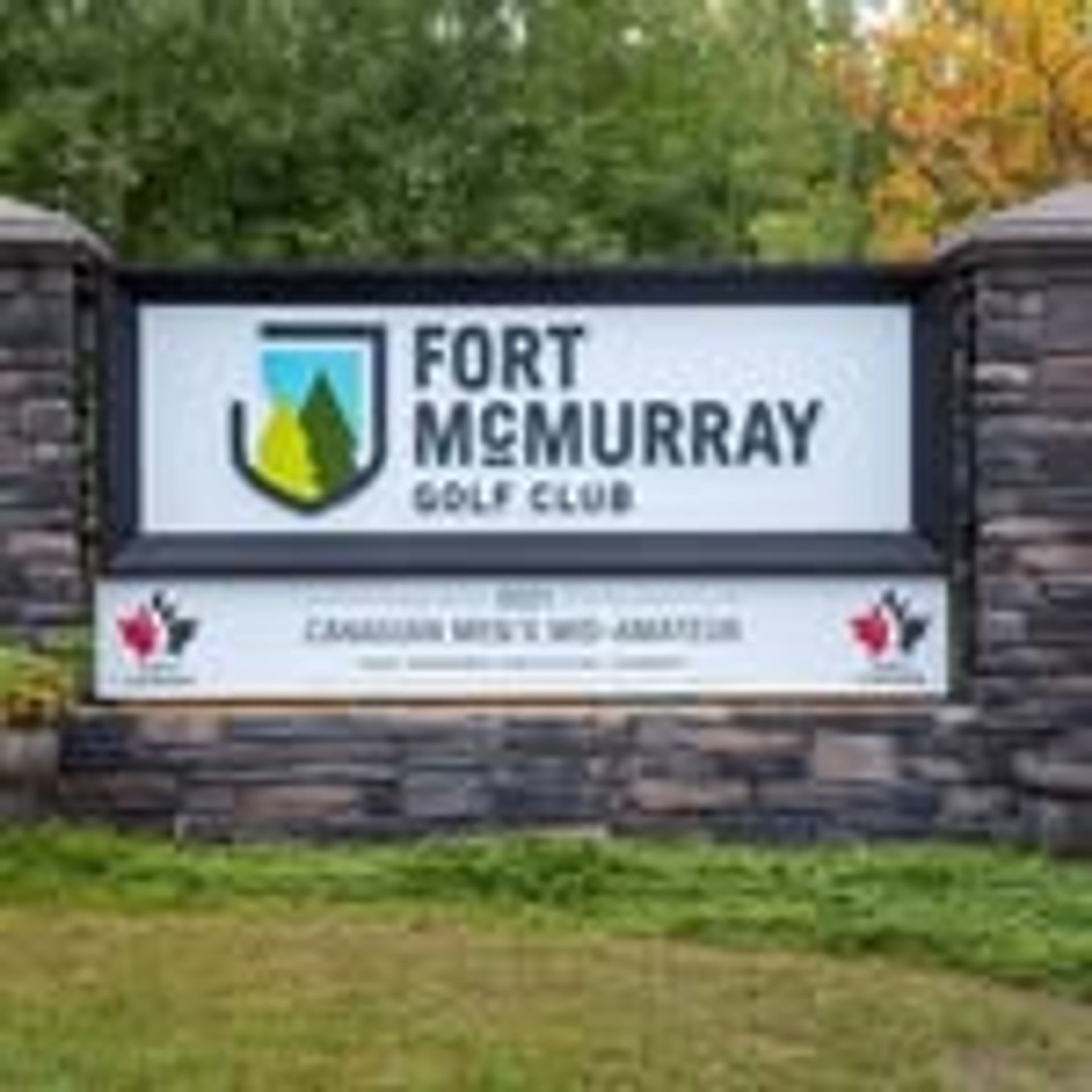 The Fort McMurray Golf Club entrance sign set in a stone frame with greenery around it.