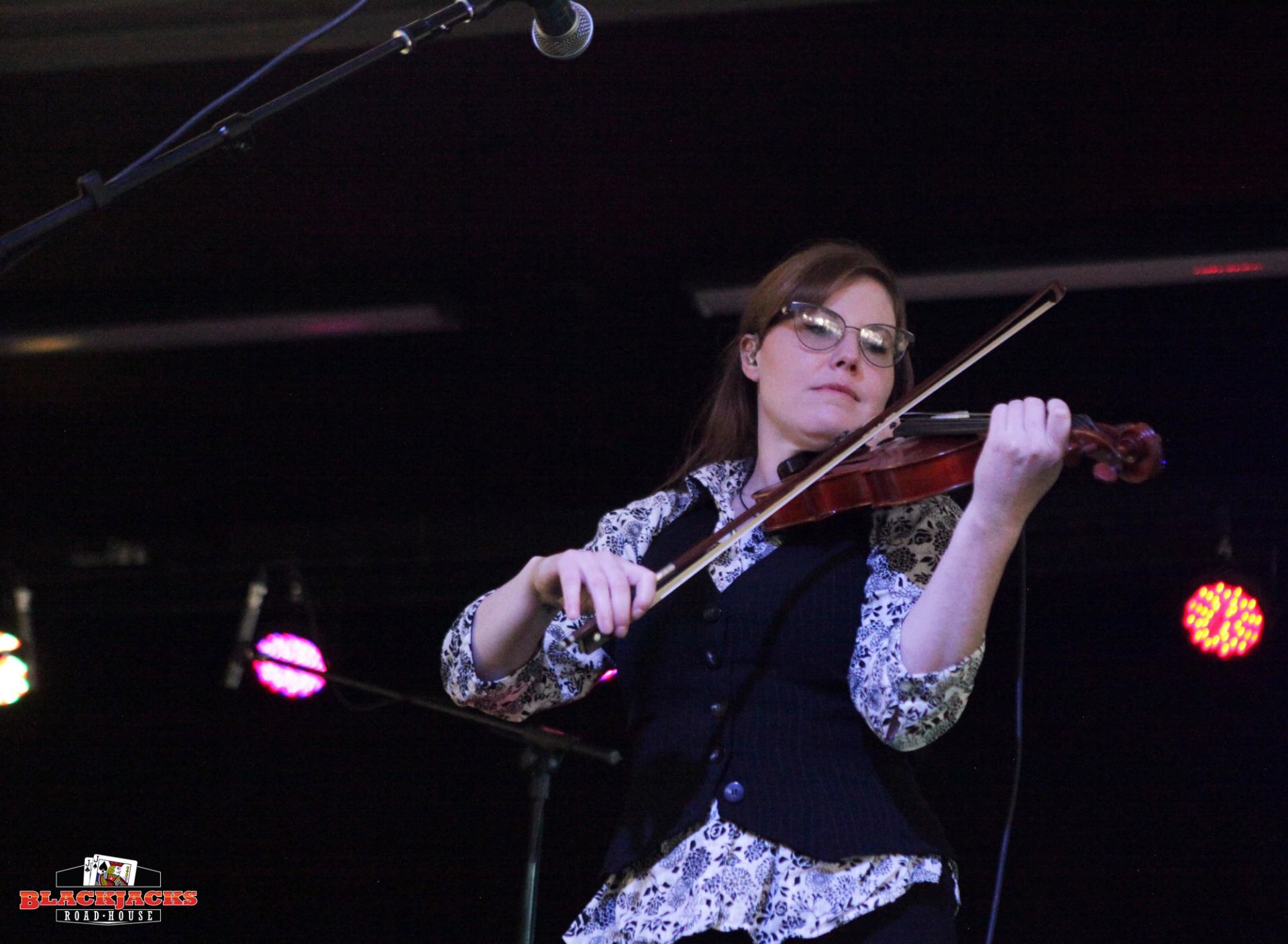 A band member playing the fiddle on stage