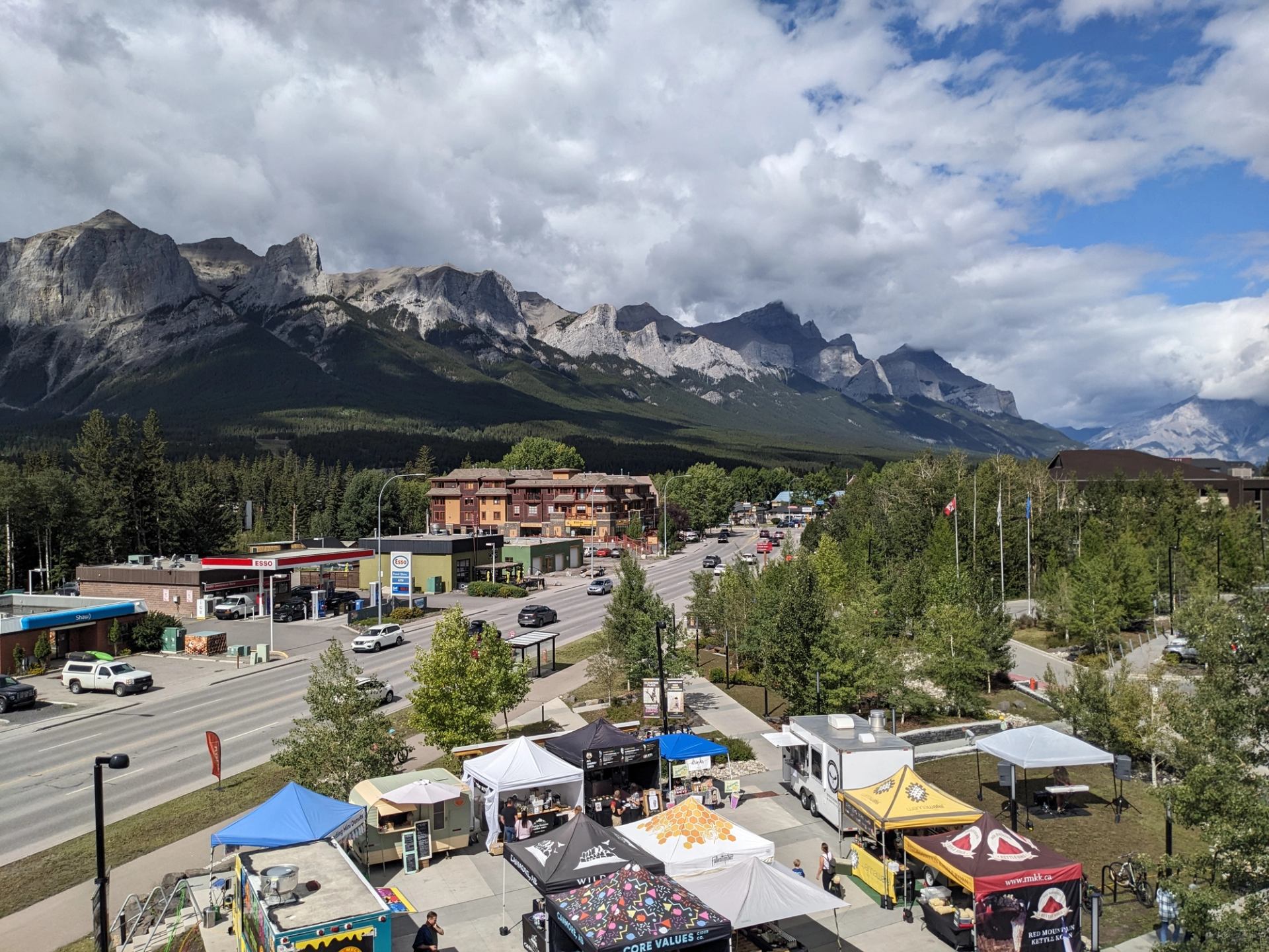 Canmore Mountain Market stalls, tents, and highway with Rocky Mountain peaks in background.