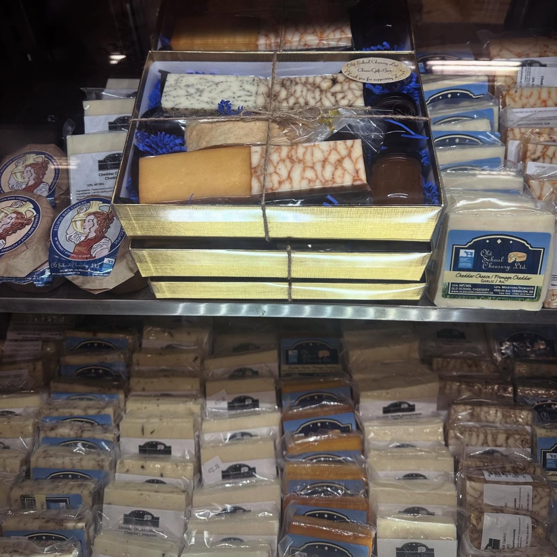 A display case filled with artisan cheeses, gift boxes, and specialty dairy products.