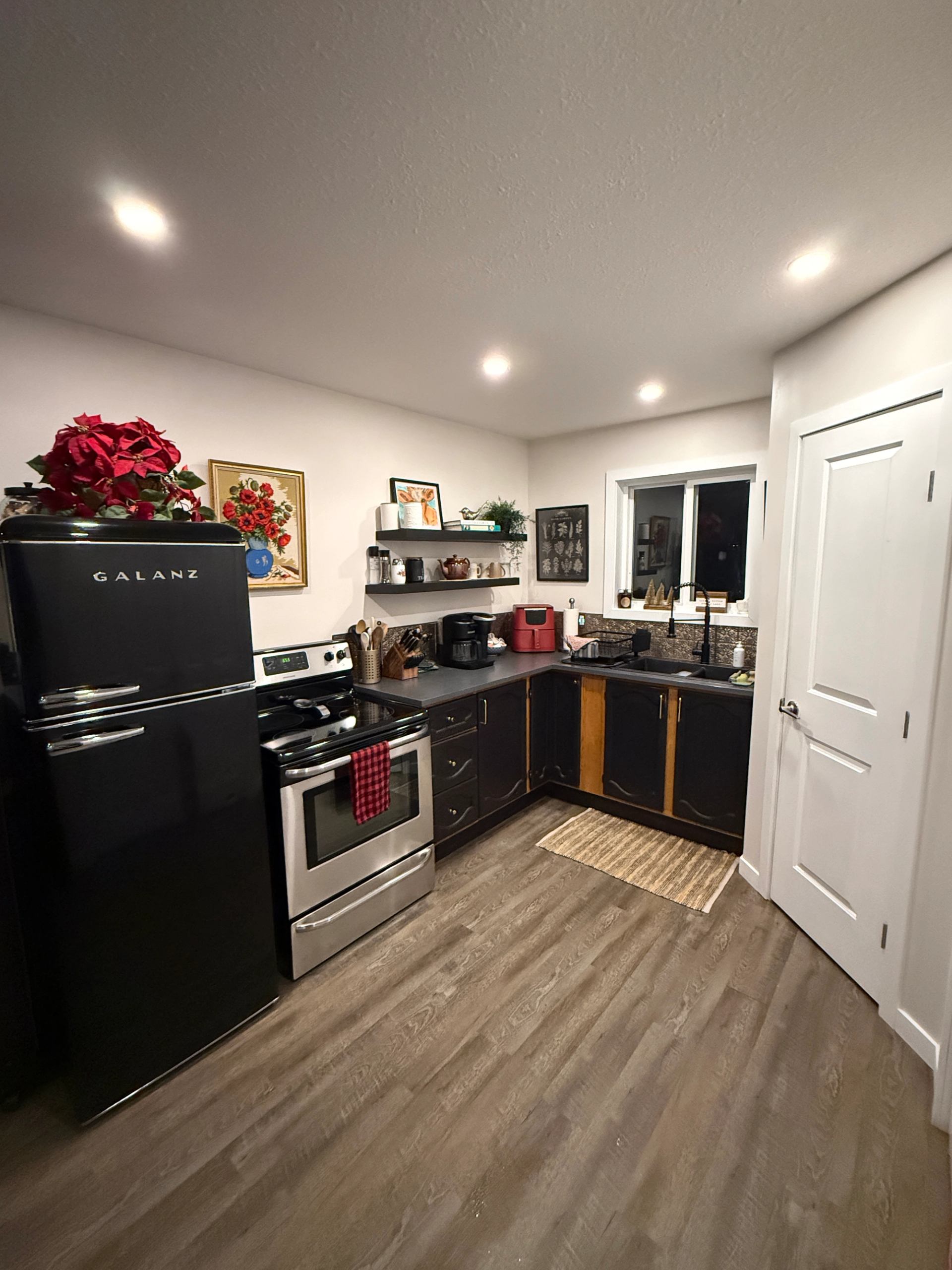 A kitchen with black cabinets, stainless appliances, and warm lighting.