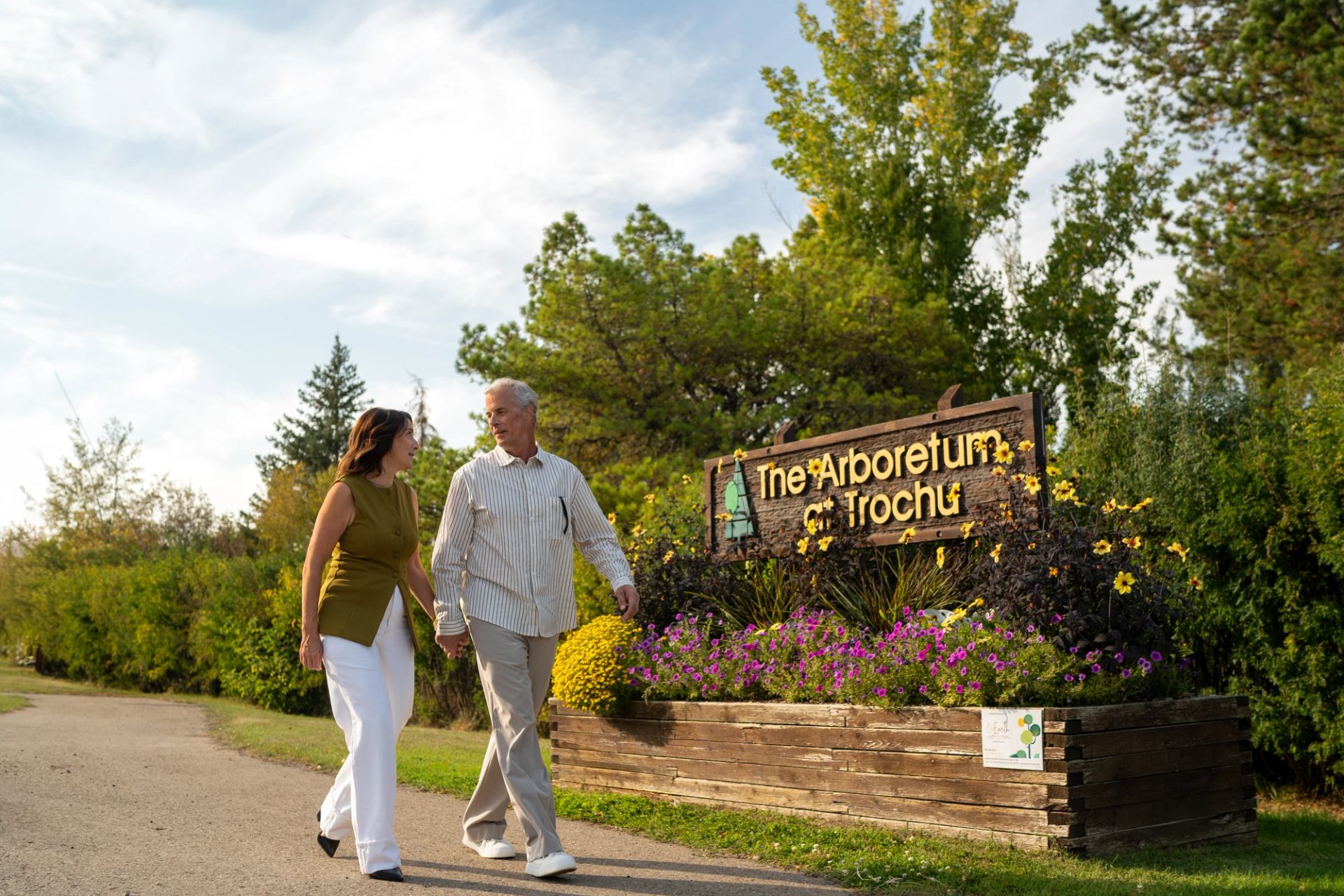 Couple walks by the sign for The Arboretum at Trochu
