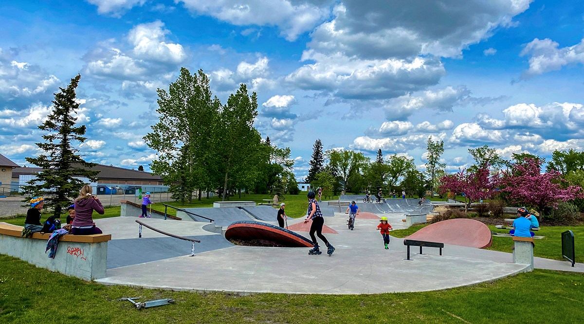 Various young people watch and use a local skatepark.