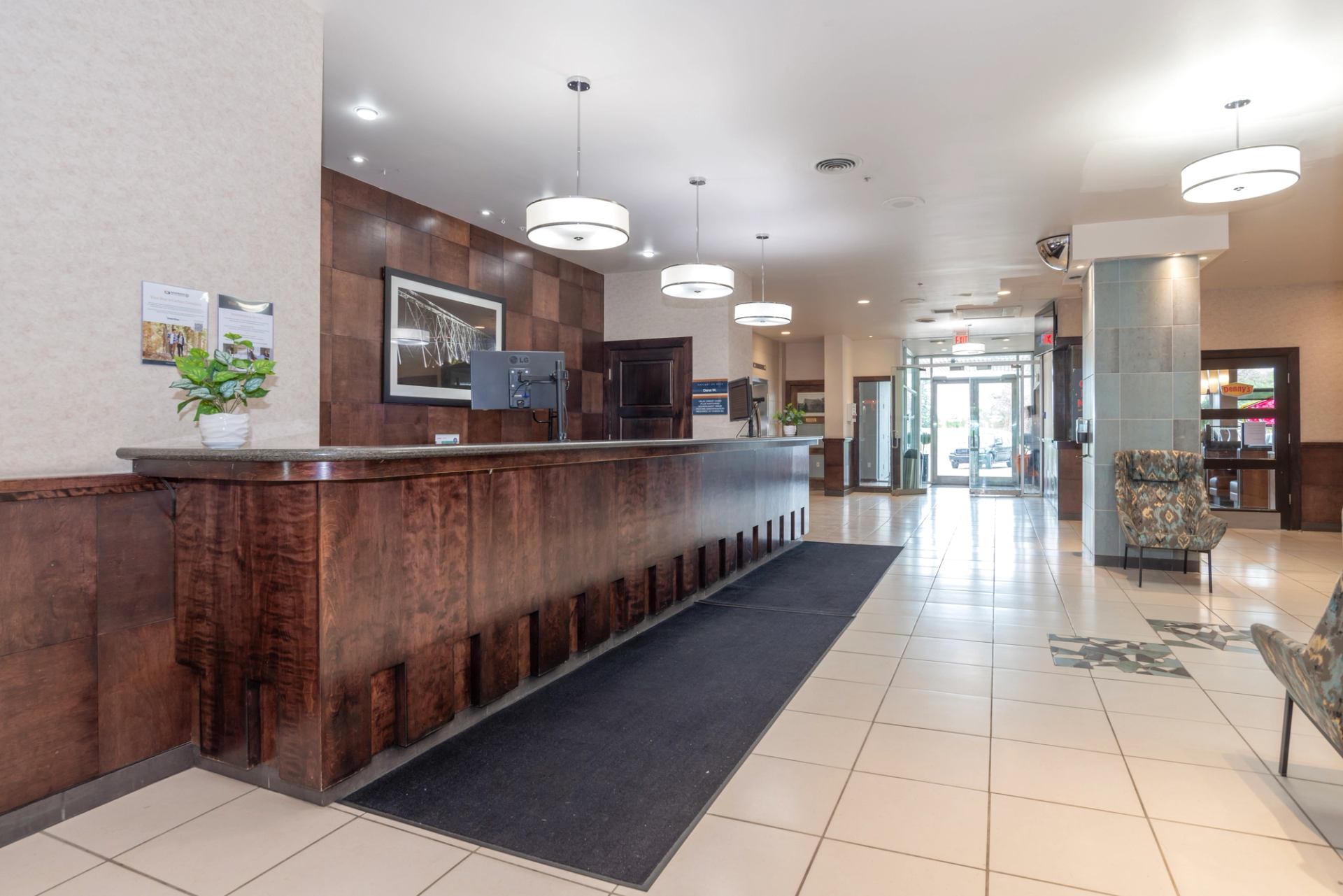 Hotel lobby front desk with warm lighting, tiled floors, and modern décor.