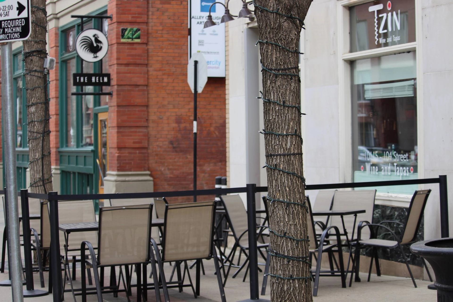 Outdoor seating at Tzin Wine and Tapas with string-lit trees and sidewalk tables.