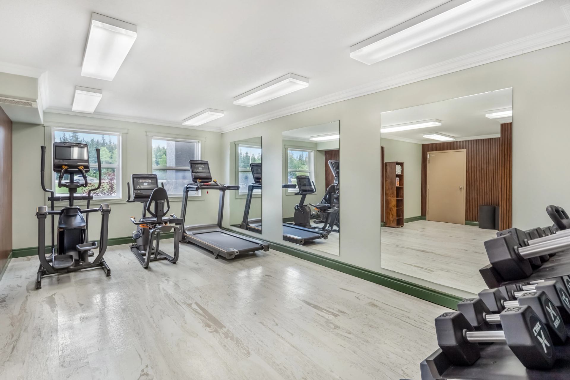 Bright, clean fitness room with treadmills, exercise bike, and free weights at Velora Hinton.