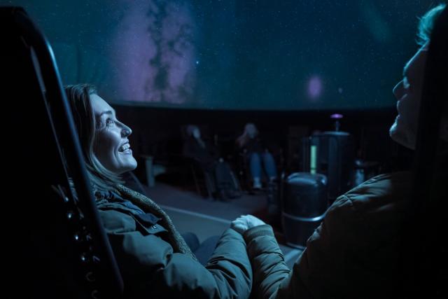 Young couple viewing projected sky in planetarium.