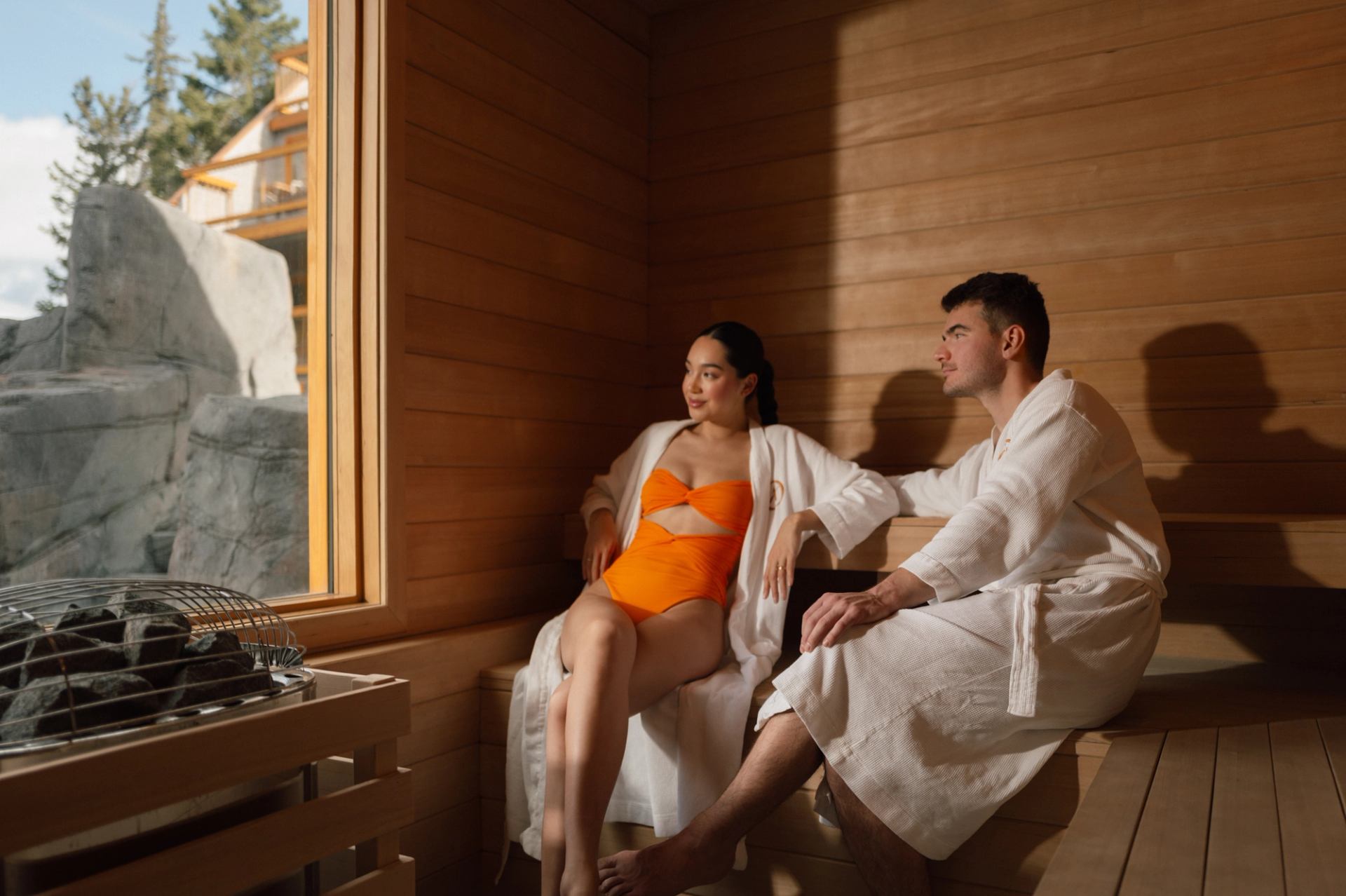 Couple lounging in wood sauna with robes on at Hotel Canoe and Suites