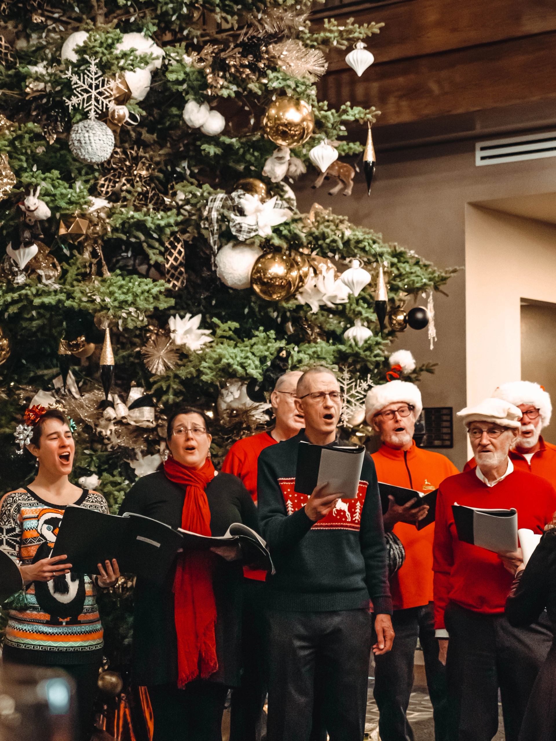 Carolers singing in front of a decorated Christmas tree at The Malcolm Hotel.
