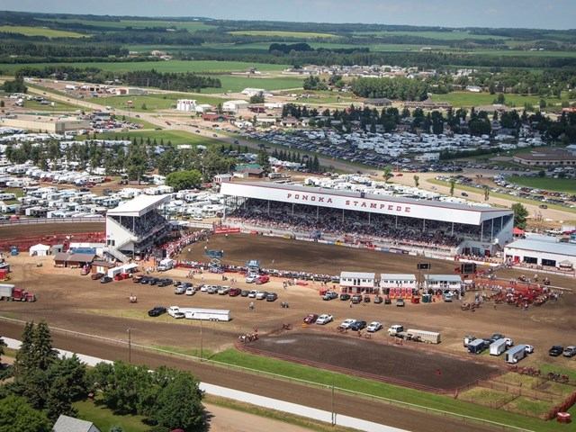 Aerial view of Ponoka Stampede grandstand, rodeo arena and surrounding fairgrounds and fields.