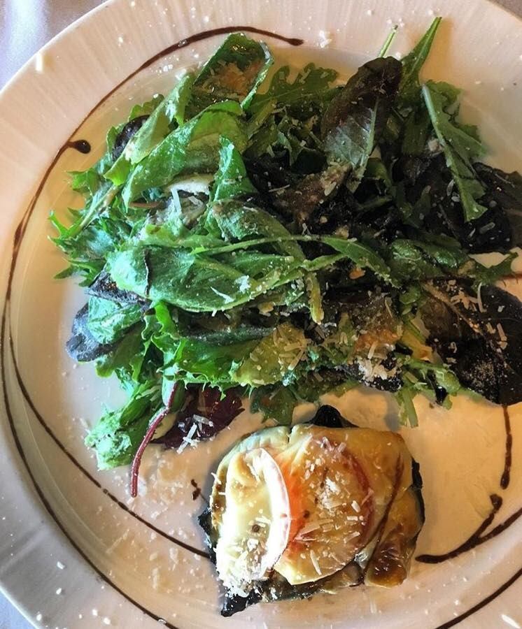 Plate with mixed greens, roasted vegetables, lemon slice, and grated cheese.