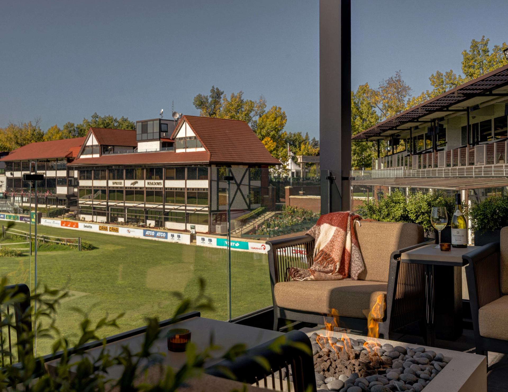Terrace seating at Foxtrot at Spruce Meadows overlooking the grounds, with lounge chairs and a fire feature.