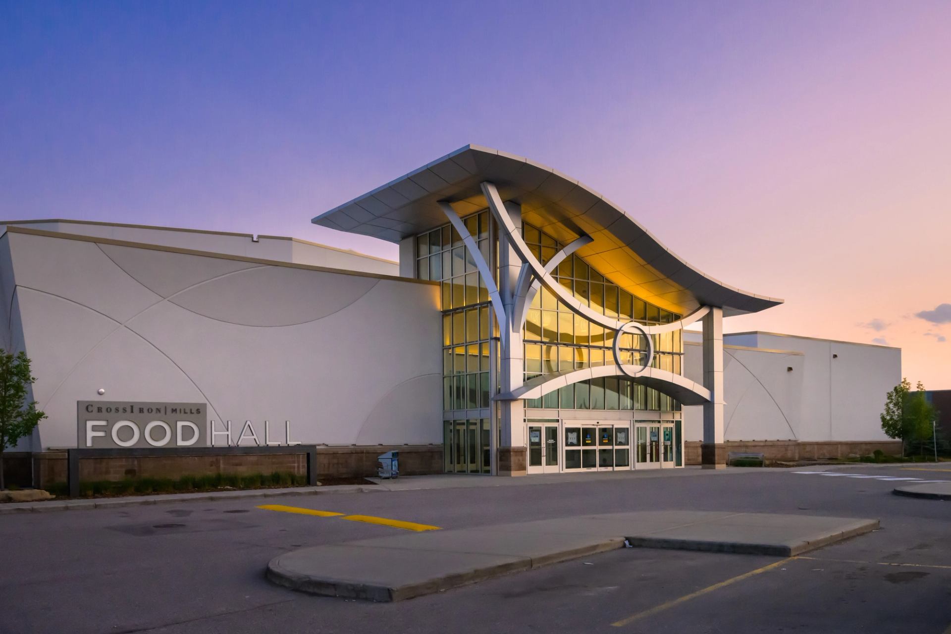 CrossIron Mills Food Hall exterior with curved roof and twilight sky.