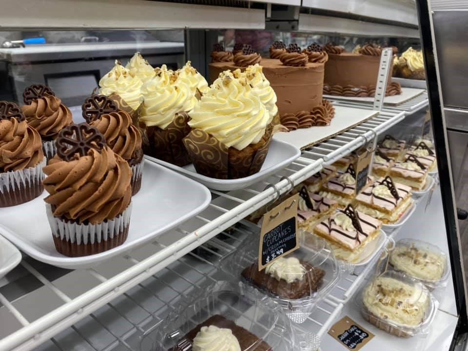 Display of chocolate and vanilla cupcakes with cakes at Lakeview Bakery & Deli.