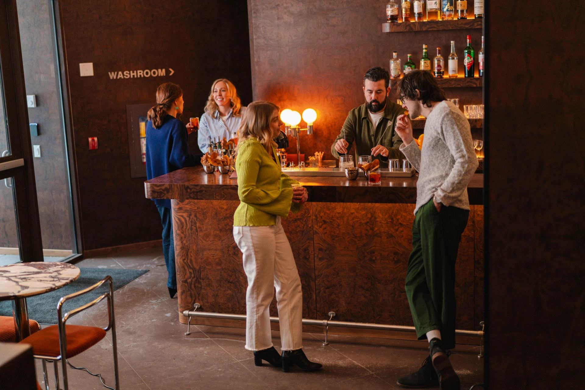 People stood around enjoying drinks at the bar at Bar Henry.