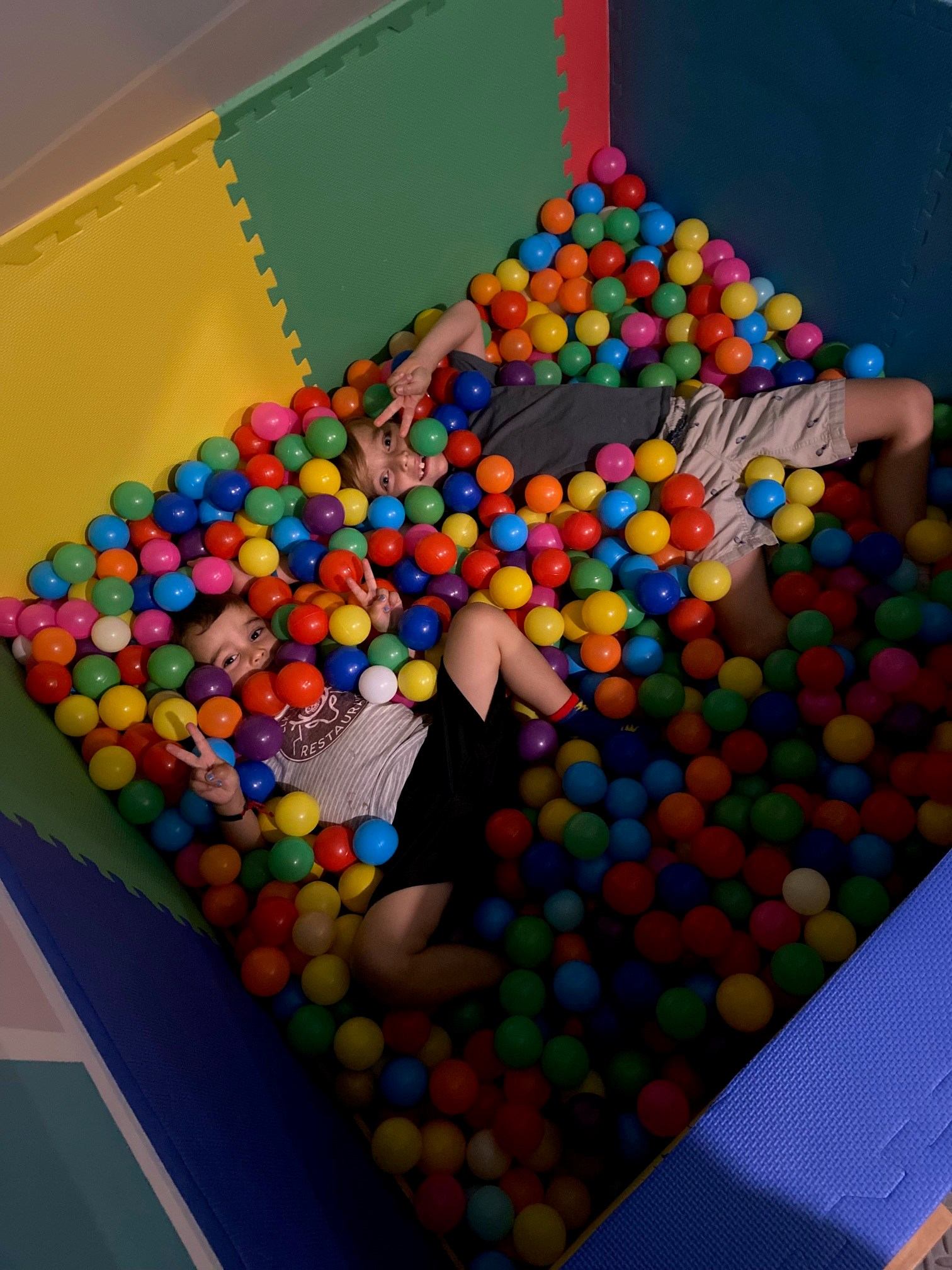 Two people relaxing in a colorful ball pit at Cubz Play Cafe.