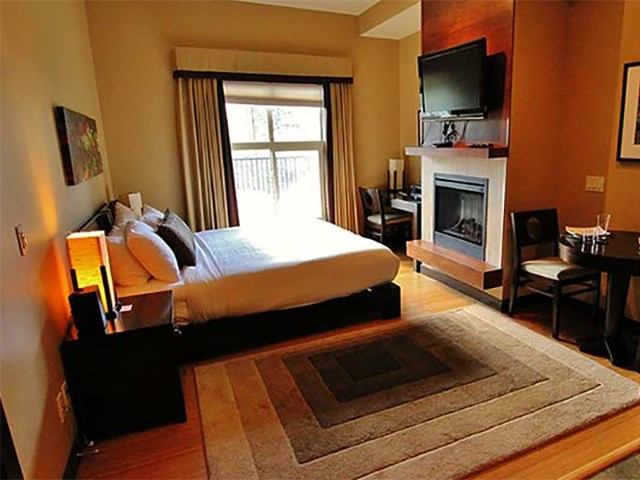Cozy lodge bedroom with fireplace, balcony, and modern furnishings.